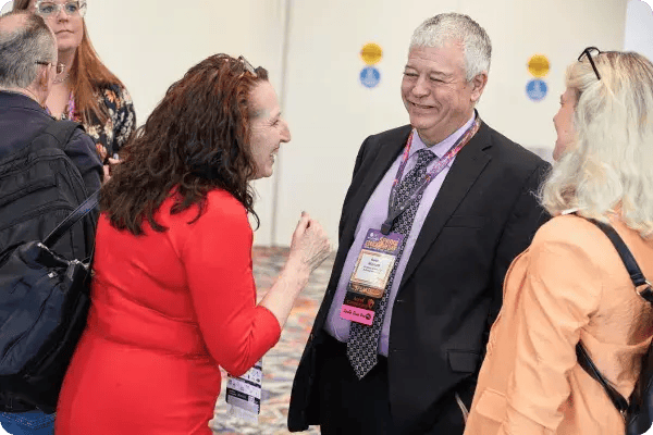 A woman smiles at a male attendee wearing an event badge