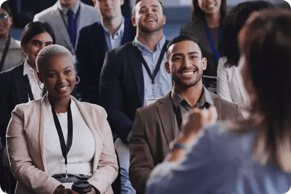 A conference speaker addresses a crowd of smiling attendees