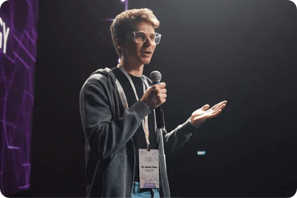 A tech conference keynote speaker wearing a badge on stage