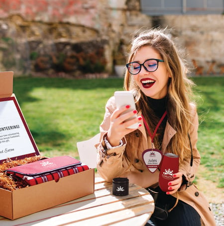 A woman watches a live event from her phone with branded gifts