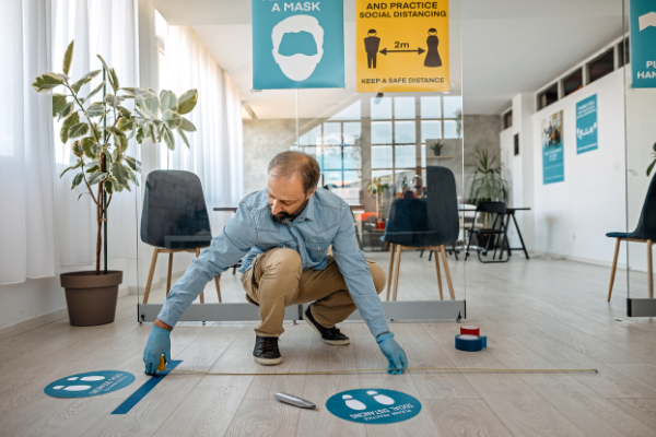 Staff member places social distancing stickers on the floor