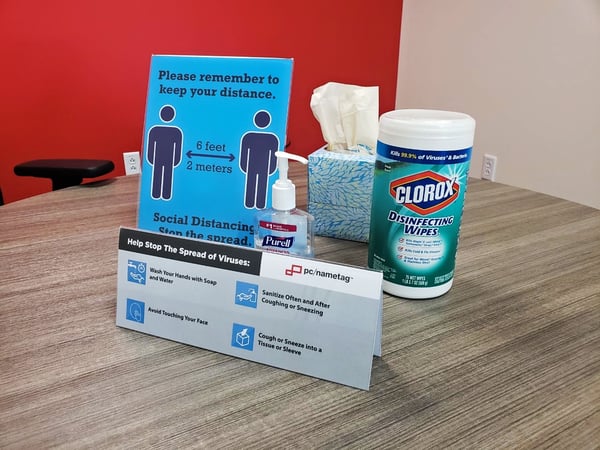 Table with hand sanitizer, wipes and social distancing signs