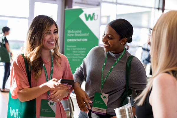 two young women attend a sustainable student orientation wearing eco event passes and recyclable lanyards