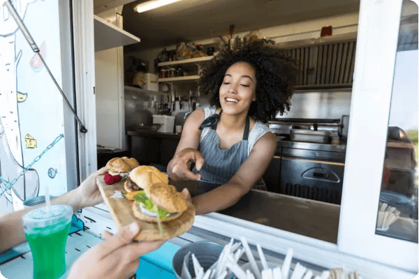 african american food truck owner serves a burger to a customer