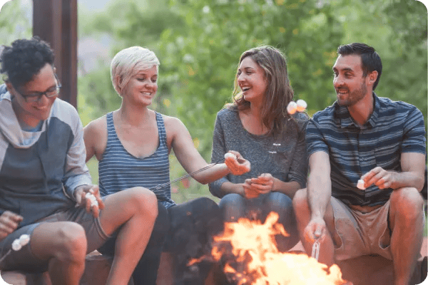 four adults roasting smores