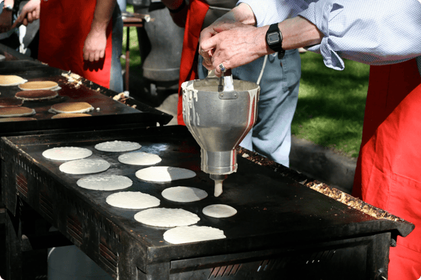 Coach raises money by making pancakes on a flattop grill