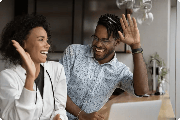 two employees smile and high five one another in an office