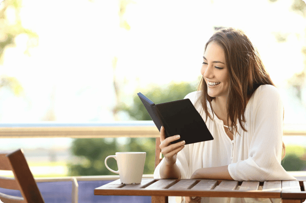 woman sits outside drinking coffee and reading a professional development book