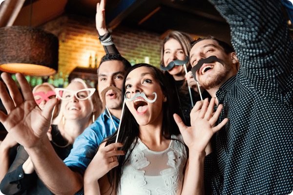 young employees pose for a selfie with fun props