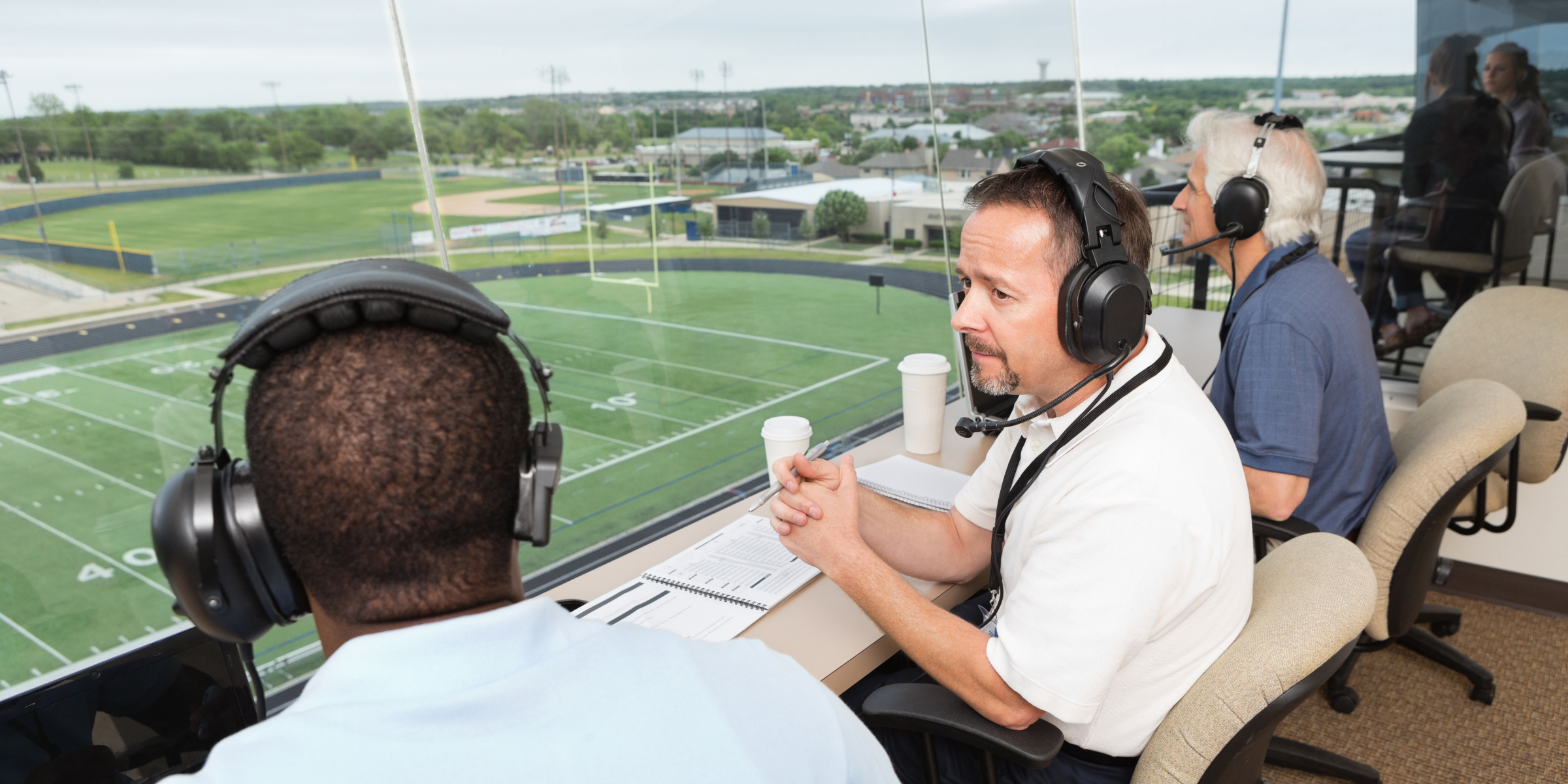 two sports moderators chat in the press box