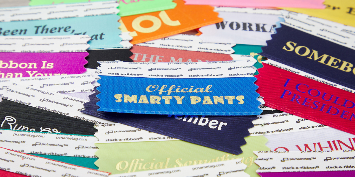 a variety of multi colored badge ribbons with fun phrases from pc/nametag