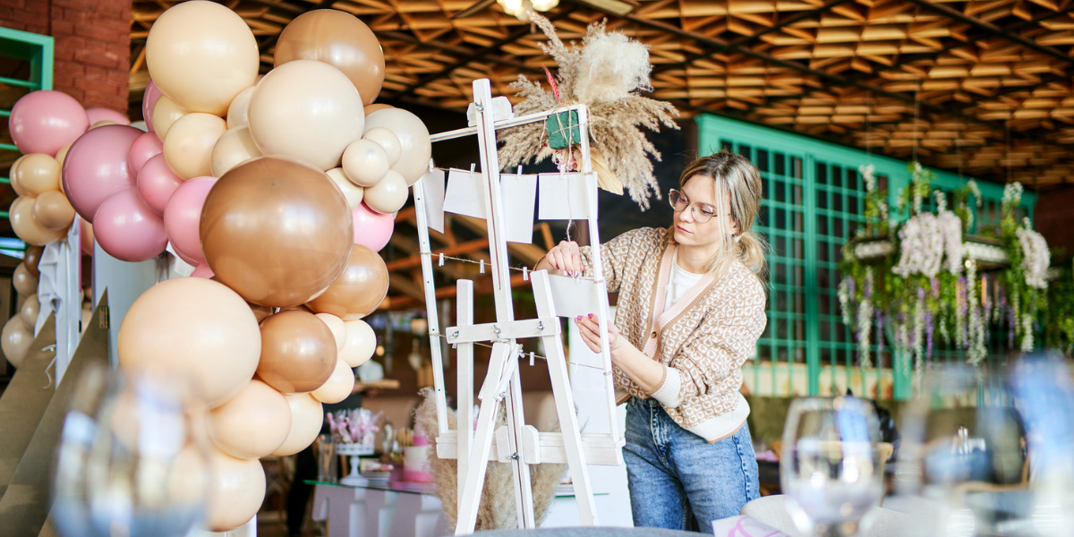 a female event planner sets up a seating chart and balloons at a party