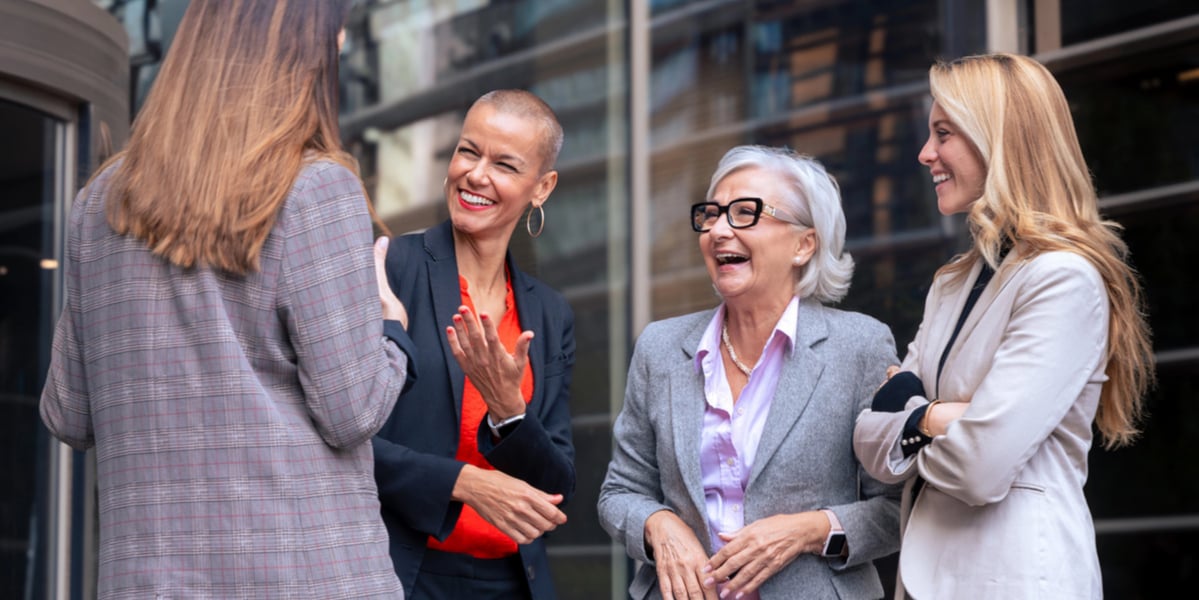 A group of female event attendees laughing outside a building