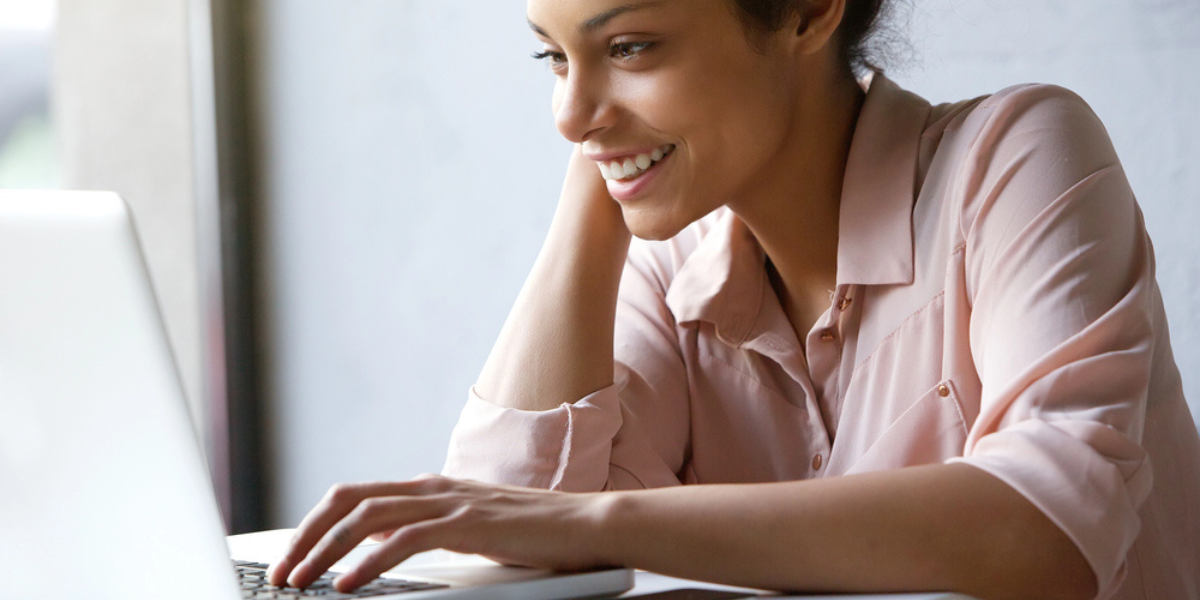 Female association manager smiling and typing on a laptop