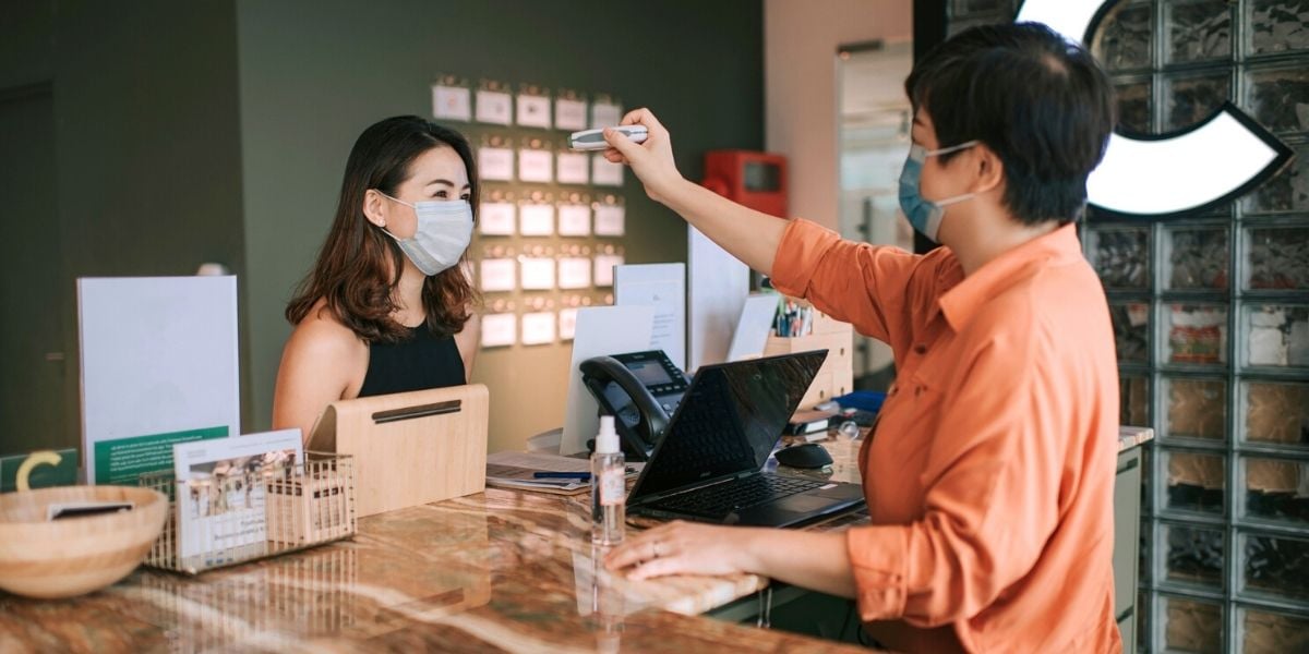 employee checking colleague's temperature at the office
