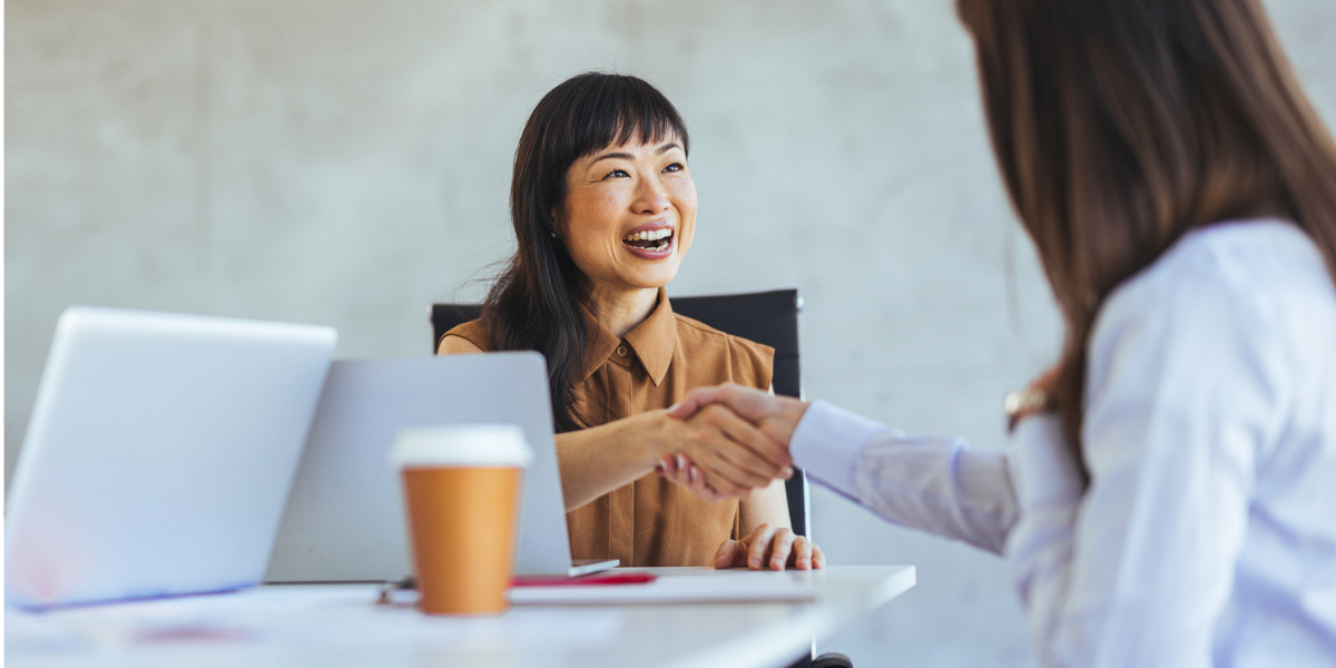 a female event planner shakes hands with a conference sponsor