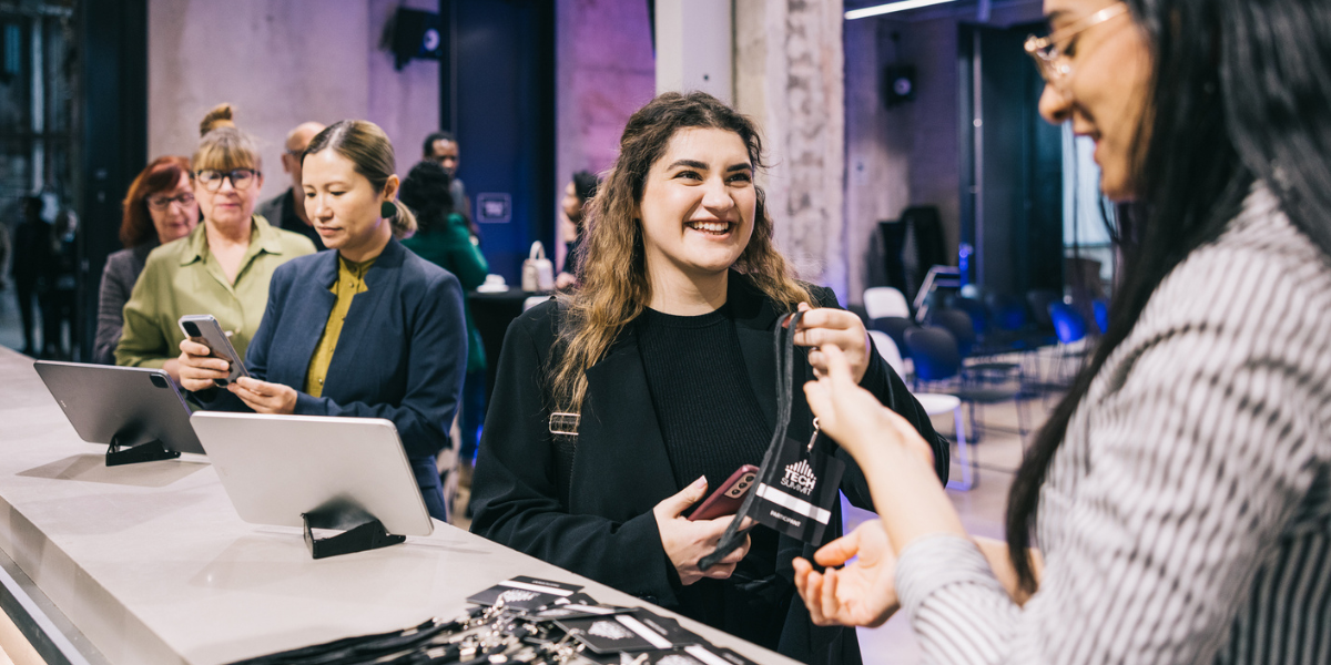 female conference attendee picks up her badge at the registration booth