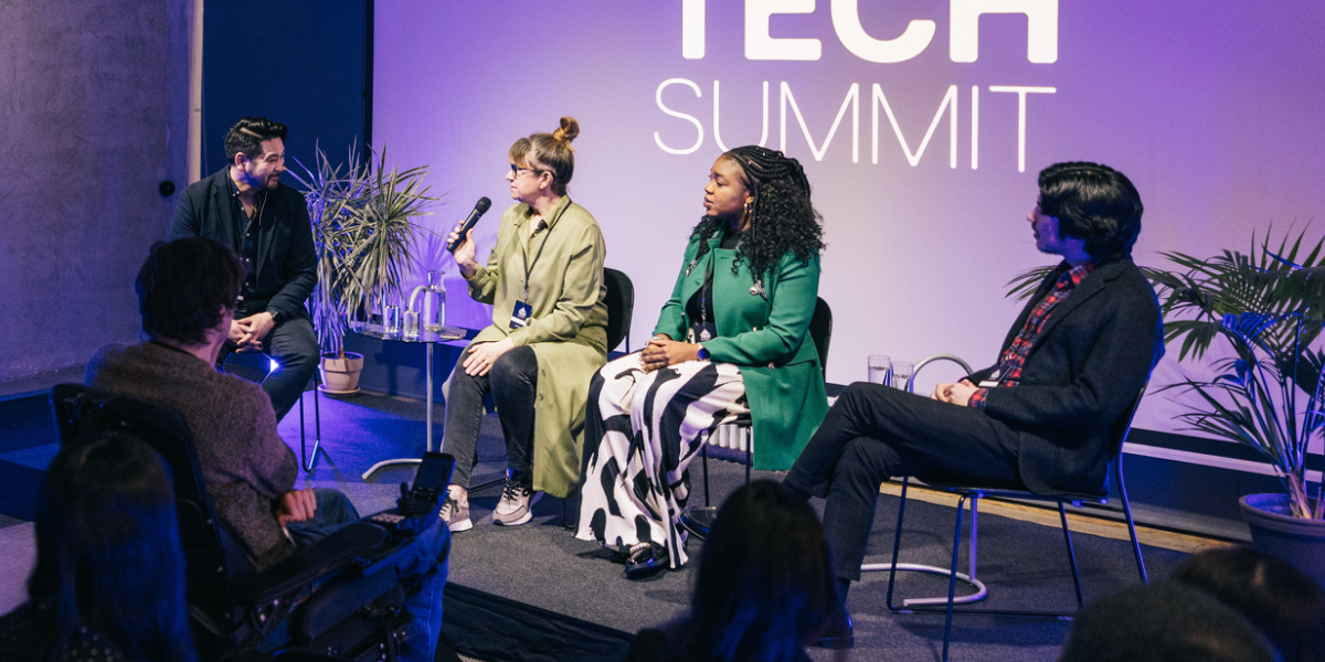 Four conference panelists give a presentation on stage