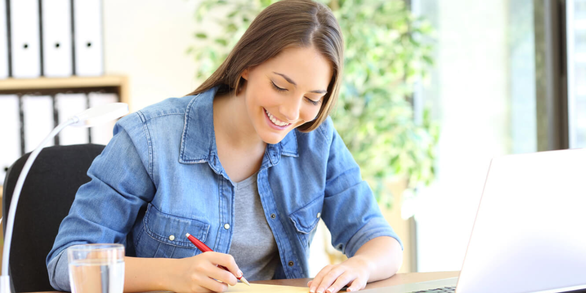 women sitting at a desk writing on paper