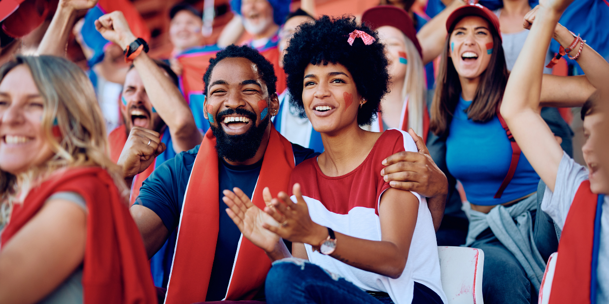 a couple wearing red, white, and blue cheers at a sports game