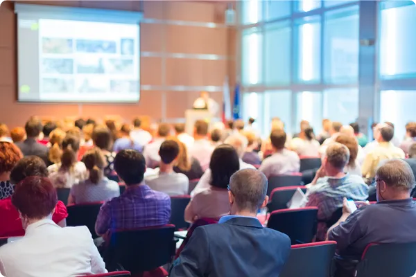 a room of conference attendees listen to a keynote speaker