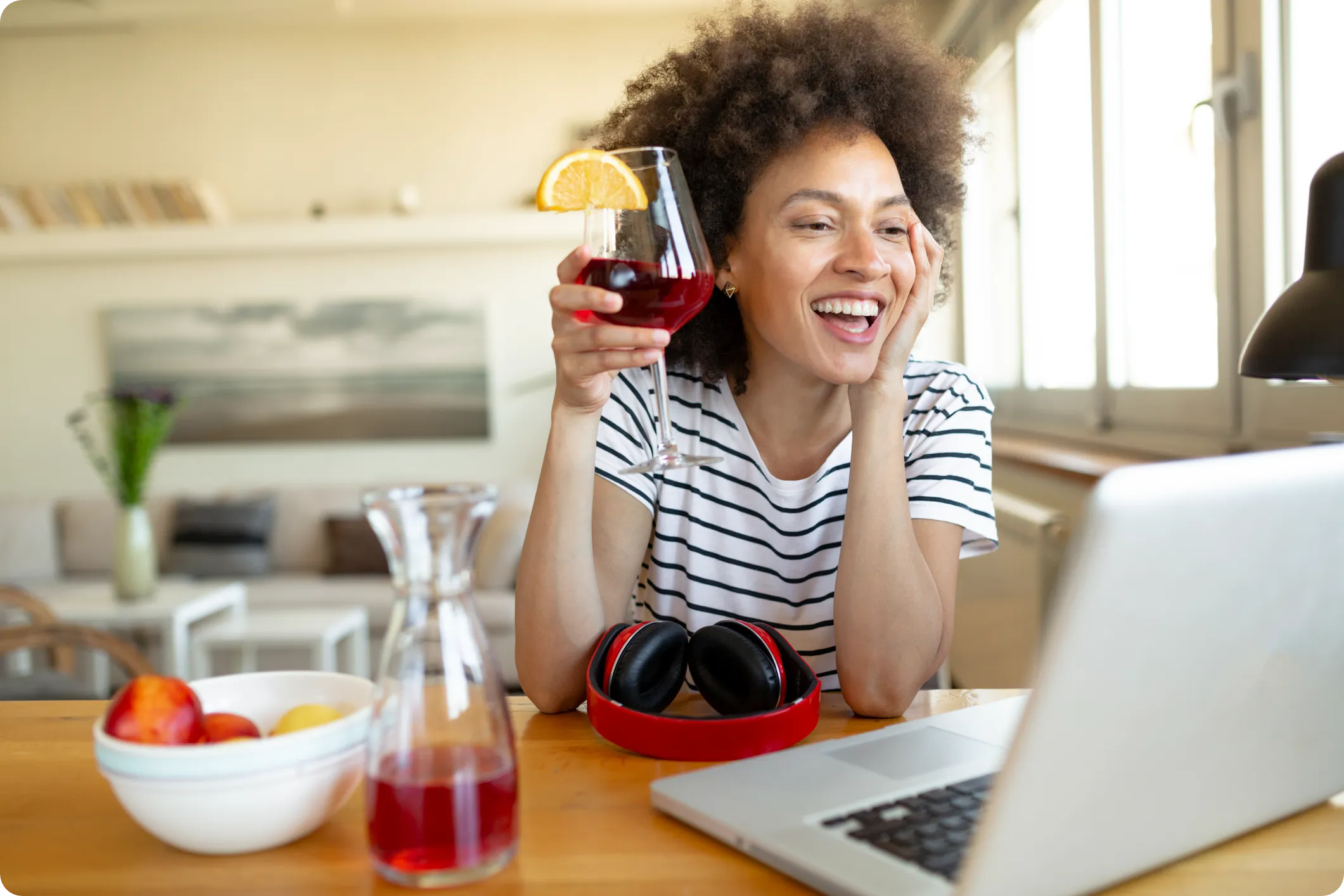 female employee participates in a virtual happy hour with a cocktail in hand