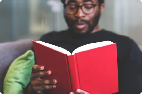 man reads a book with a red cover