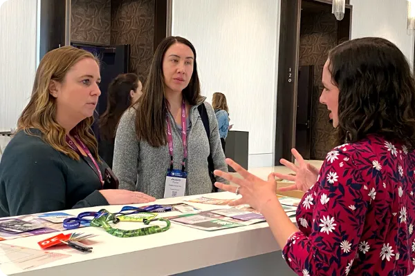 woman speaks with two customers at an event booth